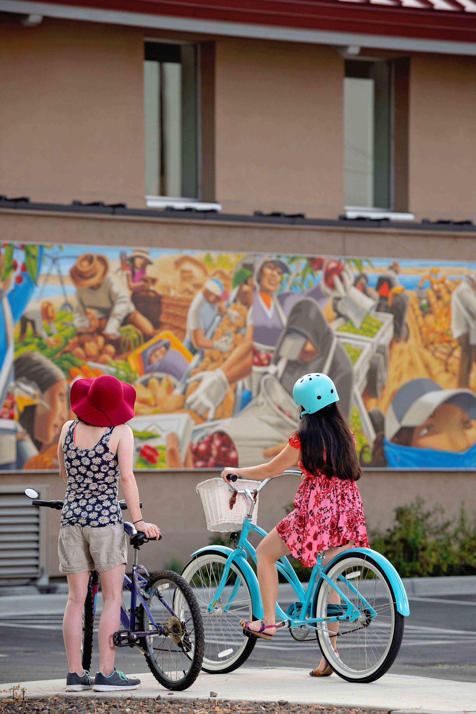 Bicyclists stop to view the Mid-Columbia Latino Heritage Mural at Columbia Gardens.