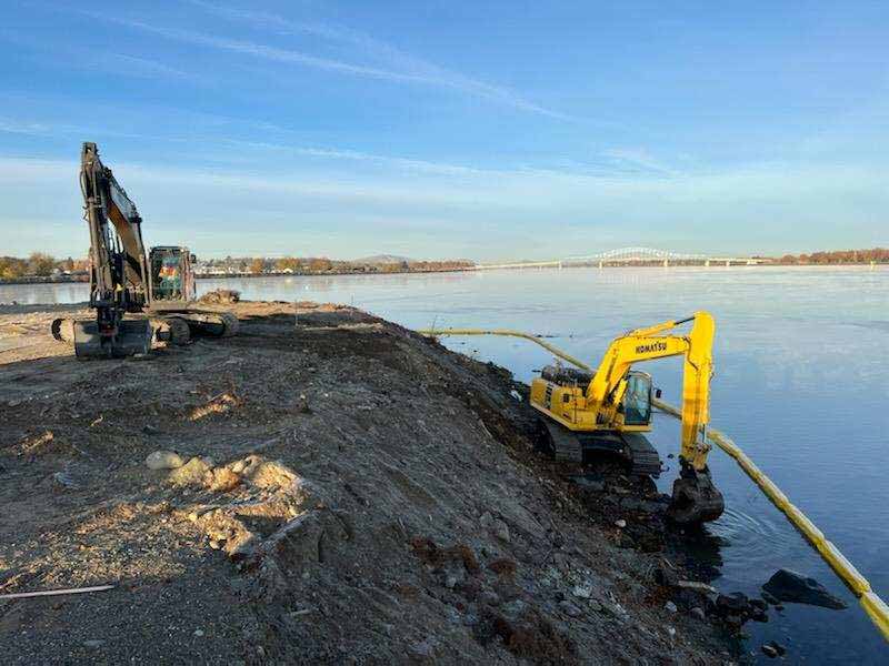 Workers use heavy equipment to remove concrete and debris from Clover Island's shoreline.