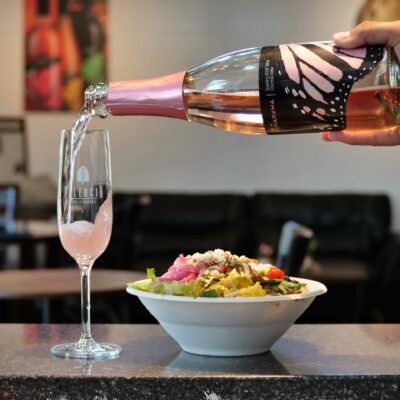 A glass of Sparkling Rosé Wine with a salad from Culture Shock Bistro.