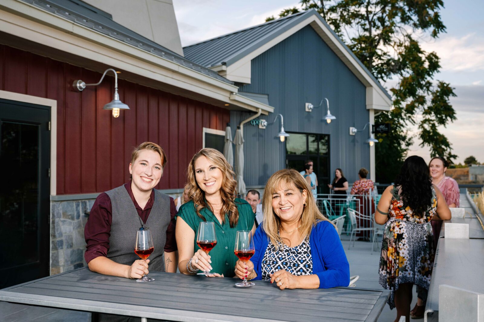 A group smiles at the camera during a beautiful fall evening at the Gordon Estate Winery's Columbia Gardens tasting room patio.