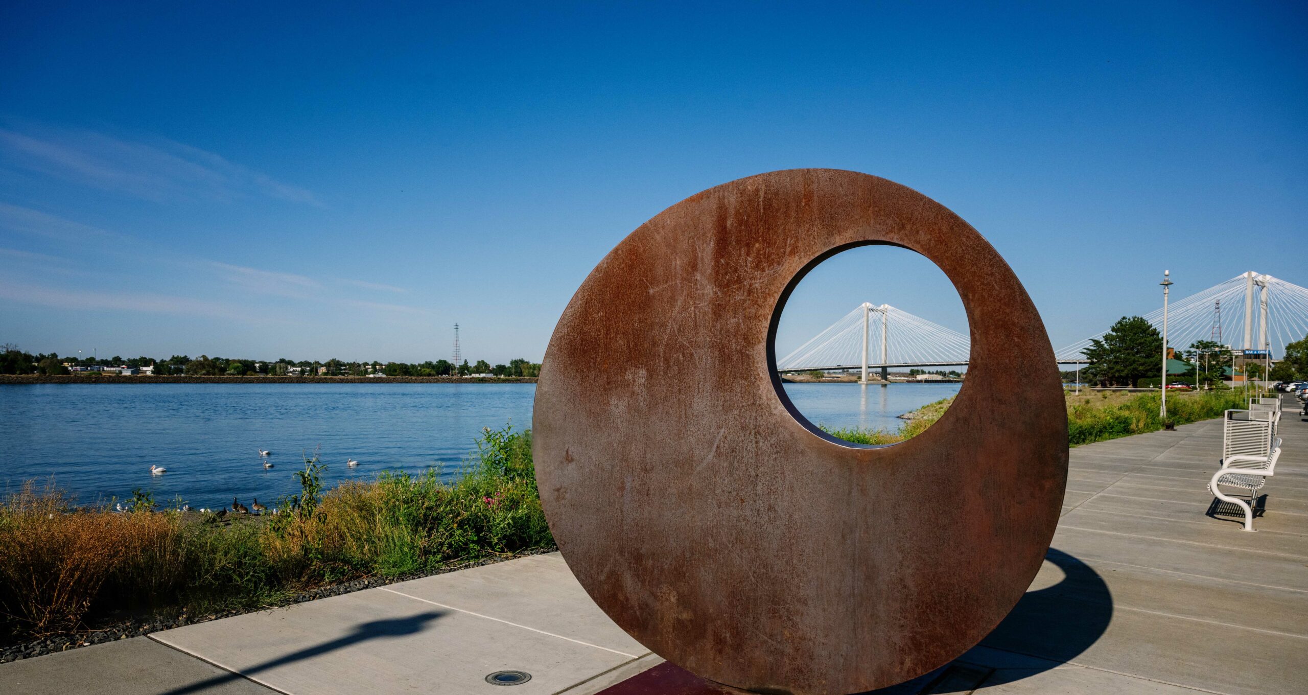 Mother of Reinvention II artwork on Clover Island with the Ed Hendler Bridge, also known as the Cable Bridge, in the distance.