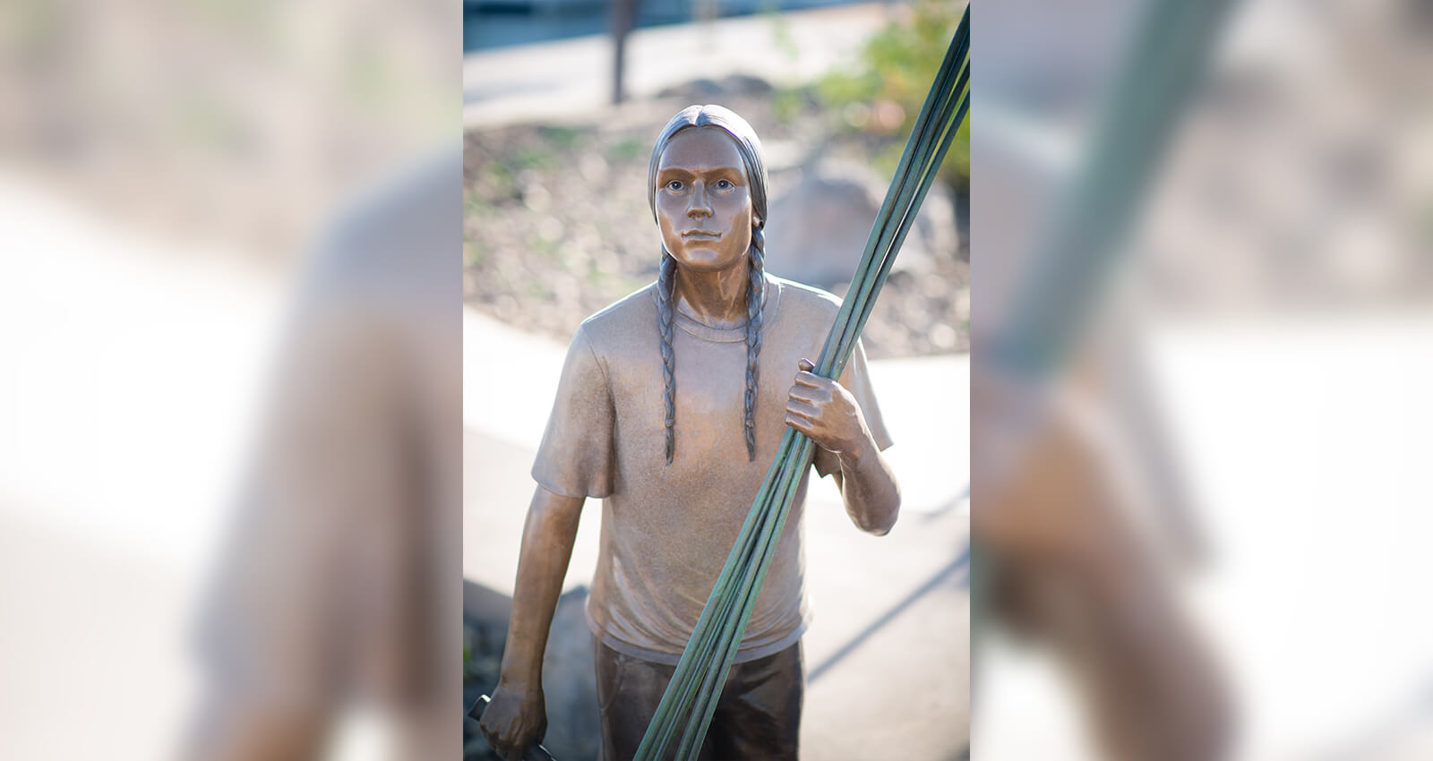 The Gathering Place Young Man sculpture holding tule reeds.